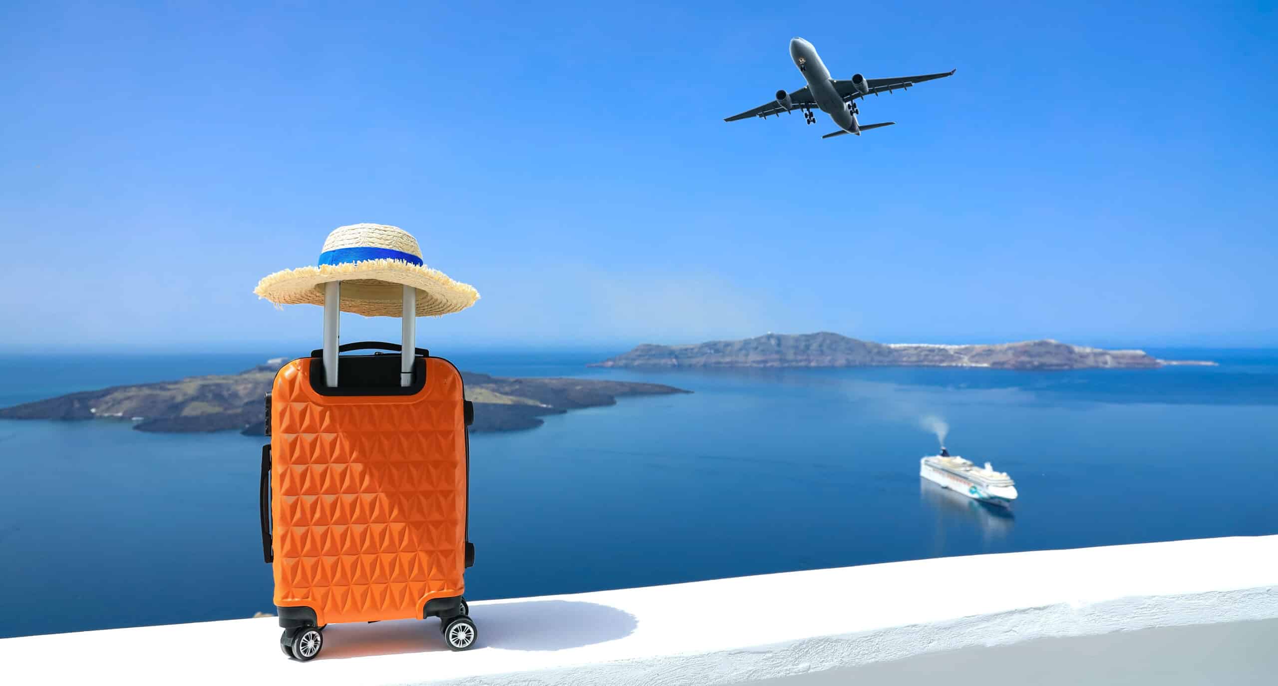 luggage and hat set on wall overlooking ocean