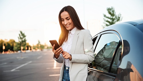 woman on phone standing next to rental car